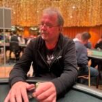 Ein Haufen von Pokerchips verschiedener Farben und Werte liegt auf einem grünen Pokertisch verstreut.