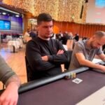 Ein Mann und eine Frau spielen Poker am Tisch, während sie Karten halten und Chips stapeln.