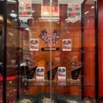Ein Mann und eine Frau spielen Poker an einem eleganten Tisch in einem luxuriösen Casino. Der Mann trägt einen schwarzen Anzug und die Frau ein rotes Abendkleid. Karten und Jetons liegen vor ihnen