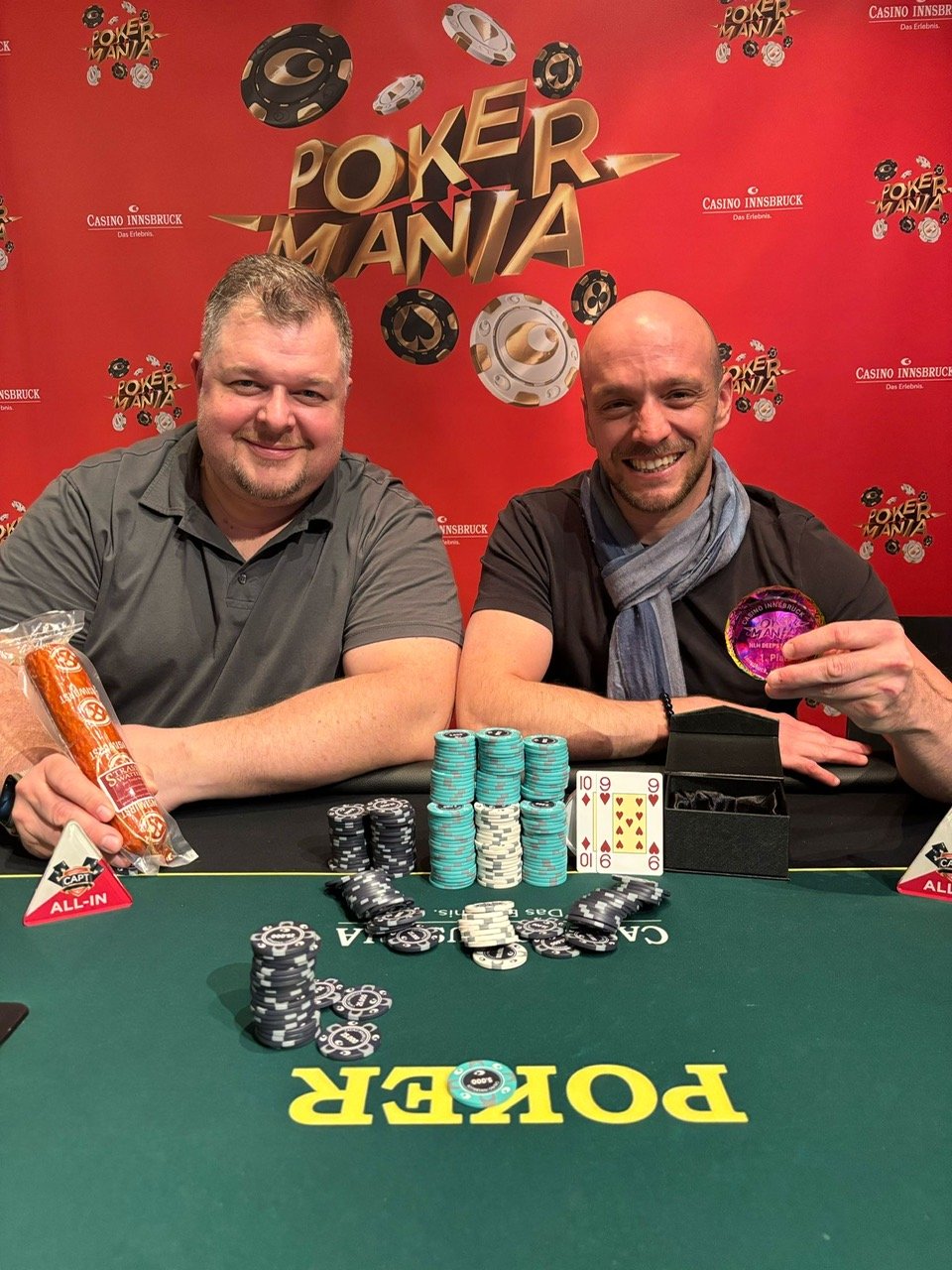 Ein Gruppenfoto von Pokerspielern bei einem Turnier, die an einem Tisch sitzen und ihre Karten halten. Hinter ihnen sind Chips und Gläser zu sehen.