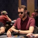 Ein Mann und eine Frau spielen Poker an einem eleganten Tisch in einem stilvollen Casino. Der Mann hat eine Hand mit Karten, während die Frau nachdenklich ihre Chips betrachtet. Die Atmosphäre ist gedämp