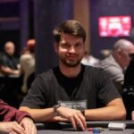 Ein bunter Pokertisch mit Spielkarten, Pokerchips und Getränken, umgeben von konzentrierten Spielern in einem eleganten Raum mit gedämpftem Licht.