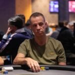 Ein bunter und lebendiger Pokertisch mit Spielkarten, Jetons und Getränken, umgeben von einer Gruppe von Menschen, die konzentriert und unterhaltsam spielen.