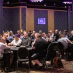 Alt-Text: Ein Mann und eine Frau spielen Poker an einem Tisch. Der Mann hat einen Stapel Chips vor sich liegen, während die Frau ihre Karten betrachtet. Beide haben konzentrierte Gesichtsausdr