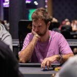 Ein Mann und eine Frau spielen Poker in einem eleganten Casino. Der Mann hält Karten in der Hand, während die Frau konzentriert auf ihre Karten schaut. Die Szene ist von einer luxuriösen Umgebung mit