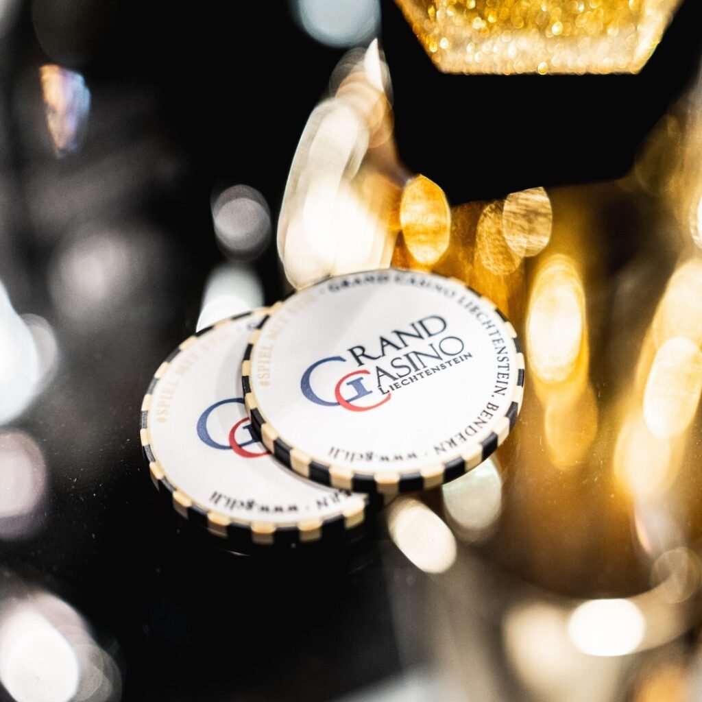 Ein Tisch mit Pokerchips und Spielkarten, umgeben von vier Personen, die konzentriert Poker spielen.