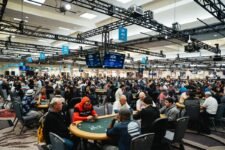 Ein voll besetzter Raum während der World Series of Poker, mit vielen Pokertischen und Spielern, die konzentriert Texas Hold'em spielen.